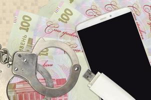 100 ukrainska hryvnias räkningar och smartphone med polis handklovar. begrepp av hackare nätfiske attacker, olaglig lurendrejeri eller skadliga program mjuk distribution foto