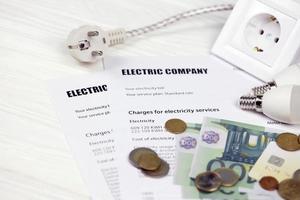 kalkylator och euro räkningar med penna på europeisk elektricitet räkningen. begrepp av sparande pengar förbi använder sig av energi besparingar led ljus lökar och elektrisk räkningen betalning foto