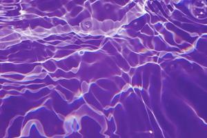 defokusering suddig transparent lila färgad klar lugna vatten yta textur med stänk, bubbla. lysande lila vatten krusning bakgrund. yta av vatten i simning slå samman. lila bubbla vatten glans. foto
