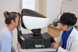 selektiv fokus på optometri ram Utrustning. medan läkare använder sig av pennljus och subjektiv refraktion till undersöka öga visuell systemet av äldre patient kvinnor med professionell maskin innan tillverkad glasögon. foto