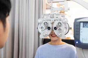 selektiv fokus på optometri ram Utrustning. medan läkare använder sig av pennljus och subjektiv refraktion till undersöka öga visuell systemet av äldre patient kvinnor med professionell maskin innan tillverkad glasögon. foto