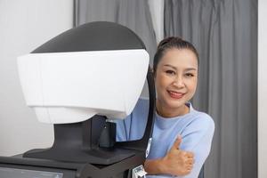 äldre asiatisk kvinnor på de optometri Utrustning. medan optiker använder sig av subjektiv refraktion till undersöka öga visuell systemet av äldre patient kvinnor med professionell maskin innan tillverkad glasögon. foto