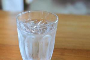 glas av kall vatten med några is på trä- tabell. foto