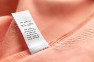 vit tvätt vård tvättning instruktioner kläder märka på rosa bomull skjorta foto