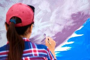 kvinnlig konstnär måla på trä duk ombord, måla abstrakt färgglad bild, utomhus festival foto