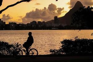 rio de Janeiro, rj, Brasilien, 2022 - människor löpning och cykling i silhuett på solnedgång på rodrigo de freitas lagun foto