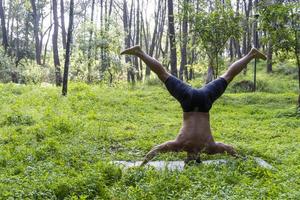 latin amerikan man håller på med yoga hållning, yoga hållning, bi bakåt prsthatah brahmara, skog foto