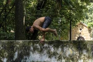 latin amerikan man håller på med yoga hållning, yoga hållning, bi bakåt prsthatah brahmara, skog foto