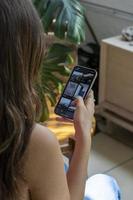 ung latinamerikan kvinna, ser på henne cell telefon kontroll henne social nät foto