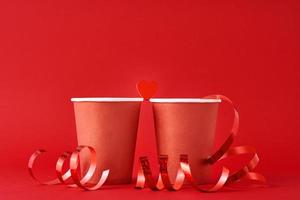 två röd papper kaffe kopp och hjärta på de röd bakgrund. romantisk och valentines dag begrepp foto