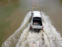 översvämmad vägar, människor med bilar löpning genom. antenn Drönare fotografi visar gator översvämning och människors bilar godkänd förbi, stänk vatten. foto