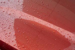regndroppar på bil. röd bil är i detaljer. foto