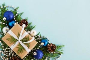 jul platt lägga sammansättning av gran grenar med gåva låda och dekorationer på de vänster hörn med kopia Plats på de blå bakgrund. foto