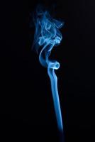 en vertikal skott av blå tobak rök på en svart bakgrund foto