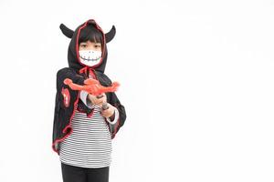 asiatisk liten flicka i en halloween kostym i en medicinsk mask . halloween med säkerhet åtgärder från covid-19 foto