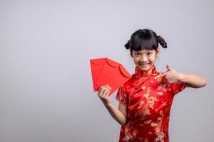 Lycklig kinesisk ny år. leende asiatisk liten flickor innehav röd kuvert foto