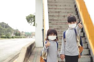 skola barn bär en ansikte mask under coronavirus och influensa utbrott. liten flicka gående tillbaka till skola efter covid-19 karantän och nedstängning. foto