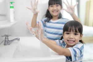liten asiatisk flickor tvätta deras händer i de badrum. mjuk fokus. kopia Plats. foto