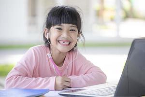 asiatisk flicka studenter uppkopplad inlärning klass studie med bärbar dator på Hem. foto