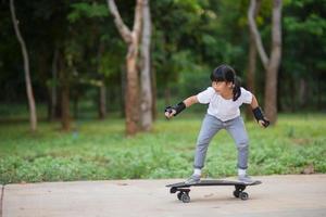 söt liten flicka spelar skateboard eller surfa skridsko i de skridsko parkera foto