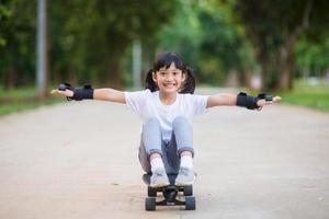 söt liten flicka spelar skateboard eller surfa skridsko i de skridsko parkera foto