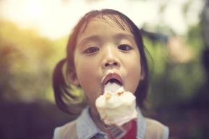 unge äter is grädde. rolig lockigt barn med glass foto