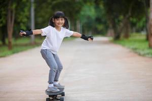 söt liten flicka spelar skateboard eller surfa skridsko i de skridsko parkera foto