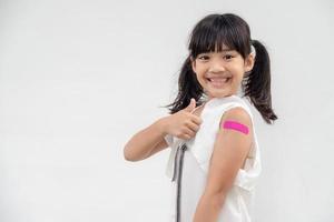 asiatisk liten flicka som visar hans ärm efter fick vaccinerade eller ympning, barn immunisering, covid delta vaccin begrepp foto