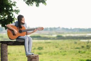 härlig tjej, spelar gitarr, sång ,musik eller lycka begrepp, solnedgång värma ljus tona effekt. foto