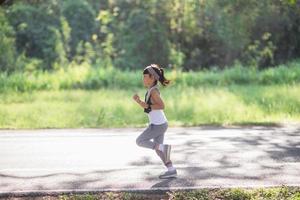 Lycklig barn flicka löpning i de parkera i sommar i natur. värma solljus blossa. asiatisk liten är löpning i en parkera. utomhus- sporter och kondition, övning och konkurrens inlärning för unge utveckling. foto