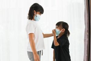 syskon liten flicka bär mask för sluta korona virus utbrott på karantän i hemmet asiatisk sibling.covid-19 coronavirus och pandemi virus symtom. foto