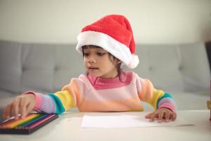 jul barn skriva brev till santa claus, unge i santa hatt skrivning önskar lista foto