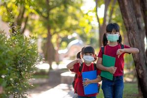 asiatisk syskon med ansikte mask gående tillbaka till skola efter covid-19 karantän och låsning foto