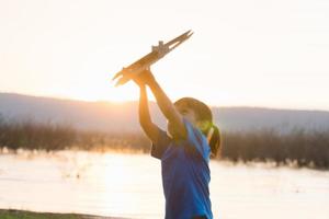 drömmar av flyg barn spelar med leksak flygplan mot de himmel på solnedgång foto