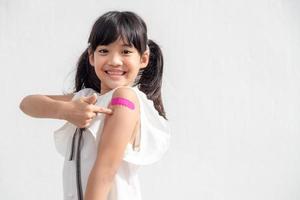 asiatisk liten flicka som visar hans ärm efter fick vaccinerade eller ympning, barn immunisering, covid delta vaccin begrepp foto