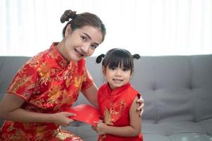 Lycklig asiatisk liten flicka mottagen röd kuvert från mor för kinesisk ny år foto