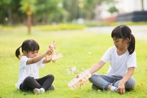 två liten barn spelar med kartong leksak flygplan i de parkera på de dag tid. begrepp av Lycklig spel. barn har roligt utomhus. foto