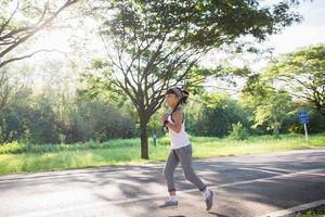 Lycklig barn flicka löpning i de parkera i sommar i natur. värma solljus blossa. asiatisk liten är löpning i en parkera. utomhus- sporter och kondition, övning och konkurrens inlärning för unge utveckling. foto