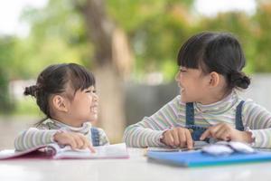 två studerande liten asiatisk flickor läsning de bok på tabell foto