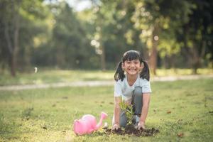närbild asiatisk barn flicka plantering en träd i grön naturen, två händer innehav och vårdande, plantor eller träd växande in i jord, värld miljö dag, jorden dag, miljö, ekologi foto