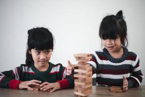glad asiatisk flicka spelar med trä- byggnad block. har roligt och inlärning kreativitet. smart unge begrepp. foto