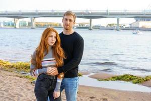 ung par är stående på de flod Bank kramas foto