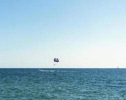 parasailing flerfärgad regnbåge fallskärm Bakom båt över blå turkos hav landskap sommar aktiviteter kopia Plats selektiv fokus foto