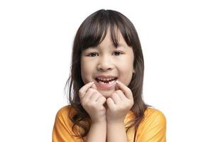 söt asiatisk flicka ler som visar henne saknas tänder i henne mun och innehav henne lösa tänder. tand förlust förbi ålder begrepp, ersättning av permanent tänder. tand avlägsnande. foto