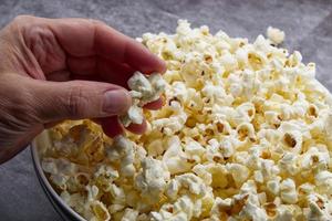 kvinna hand innehar popcorn på grå betong bakgrund. foto