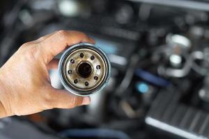 stänga upp hand en man håll gammal olja filtrera för bil underhåll begrepp i motor rum bakgrund foto