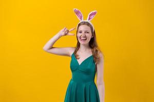 skott Lycklig flicka i fluffig rosa kanin öron, poäng fingrar till sida, demonstrerar foto