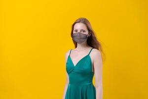 kvinna i eleganta utrusta med designer skyddande ansikte mask, grön klänning Framställ foto