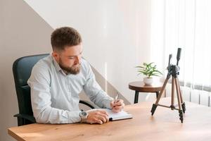 ung skäggig man med smartphone och tidtabell anteckningsblock. närbild företag foto