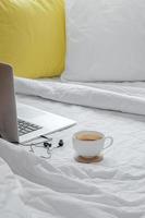 bärbar dator och espressokopp på en säng foto